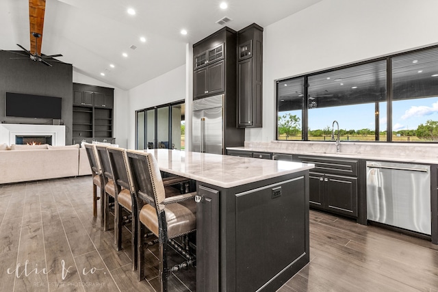 kitchen with a breakfast bar, stainless steel appliances, ceiling fan, wood-type flooring, and a kitchen island