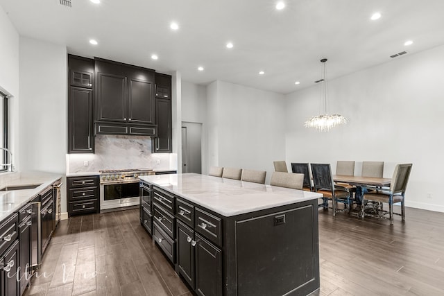 kitchen with hanging light fixtures, dark wood-type flooring, light stone counters, a chandelier, and a kitchen island