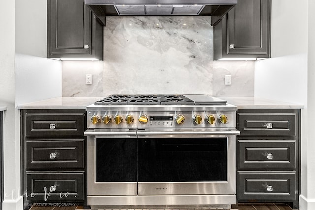 kitchen with decorative backsplash, light stone countertops, extractor fan, and range with two ovens