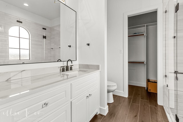 bathroom featuring walk in shower, toilet, vanity, and hardwood / wood-style flooring