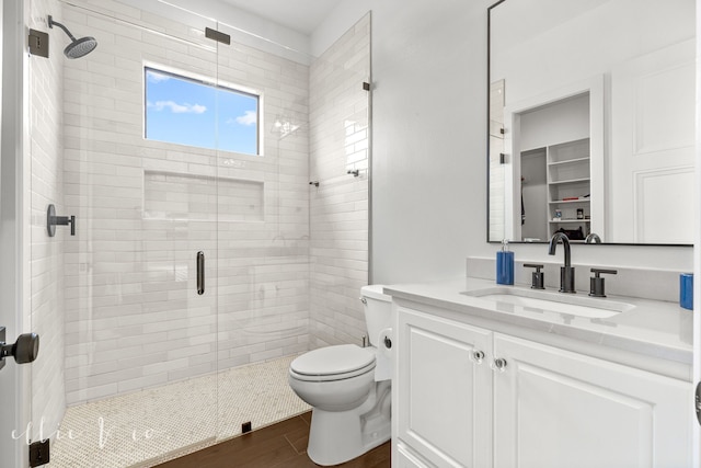 bathroom with hardwood / wood-style flooring, vanity, toilet, and a shower with shower door