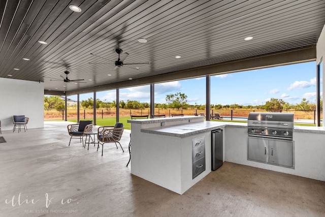 view of patio with a bar, ceiling fan, a grill, and exterior kitchen