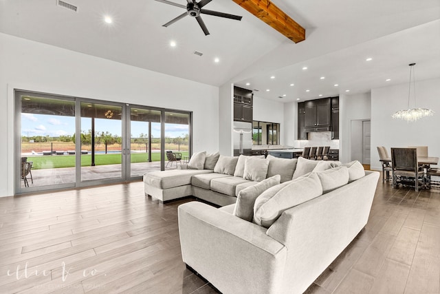 living room with beamed ceiling, light wood-type flooring, high vaulted ceiling, and ceiling fan with notable chandelier