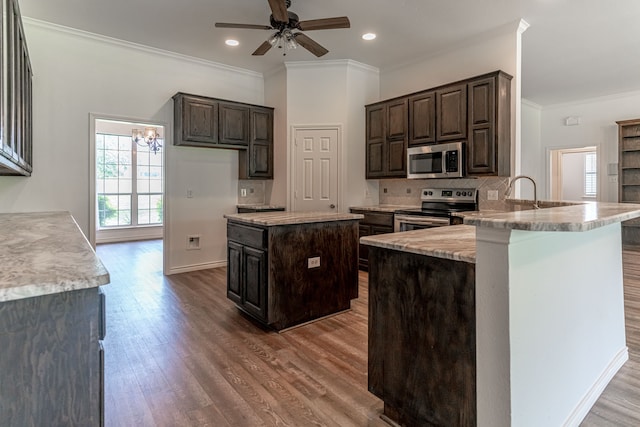 kitchen with kitchen peninsula, dark brown cabinets, stainless steel appliances, and wood-type flooring