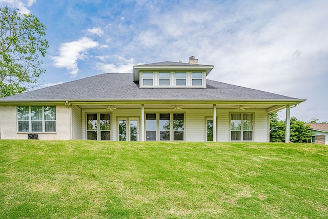 rear view of property with ceiling fan and a lawn