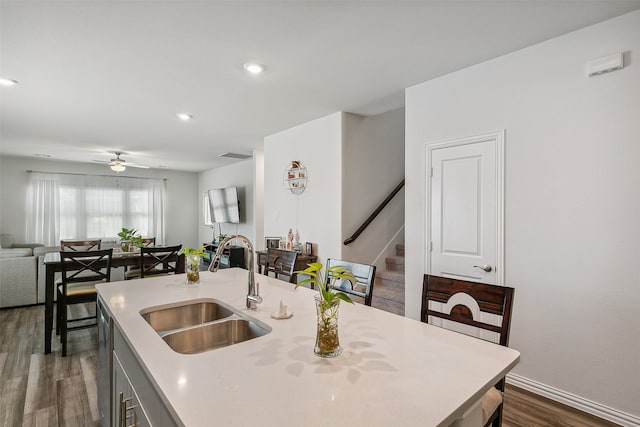 kitchen with a kitchen island with sink, dark wood-type flooring, sink, and ceiling fan