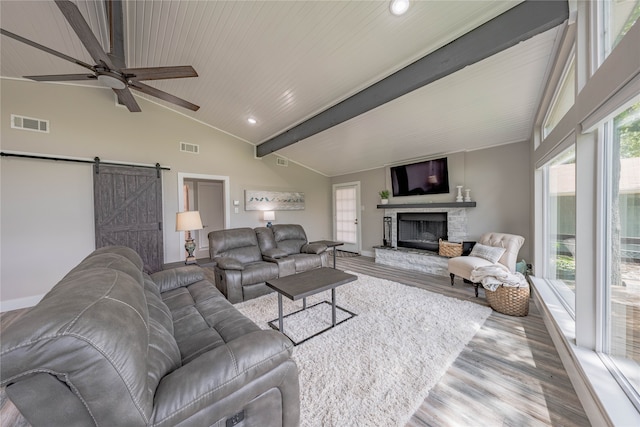 living room with lofted ceiling with beams, ceiling fan, a barn door, and light hardwood / wood-style floors