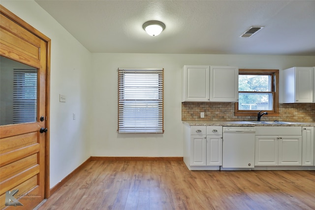 kitchen with white dishwasher, sink, tasteful backsplash, white cabinetry, and light wood-type flooring