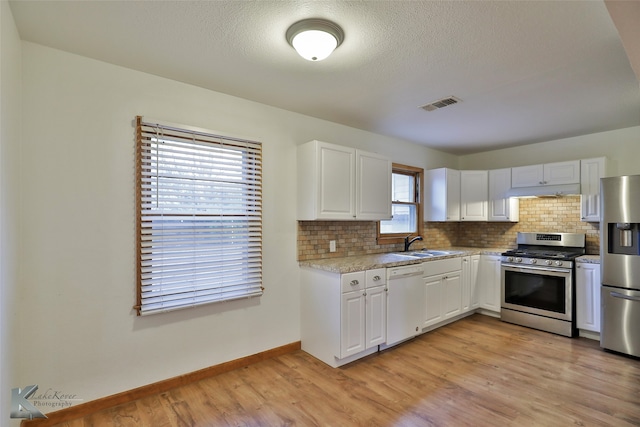 kitchen with light wood-type flooring, a healthy amount of sunlight, stainless steel appliances, and white cabinets