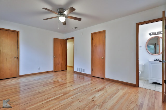 unfurnished bedroom featuring light wood-type flooring, ensuite bath, and ceiling fan