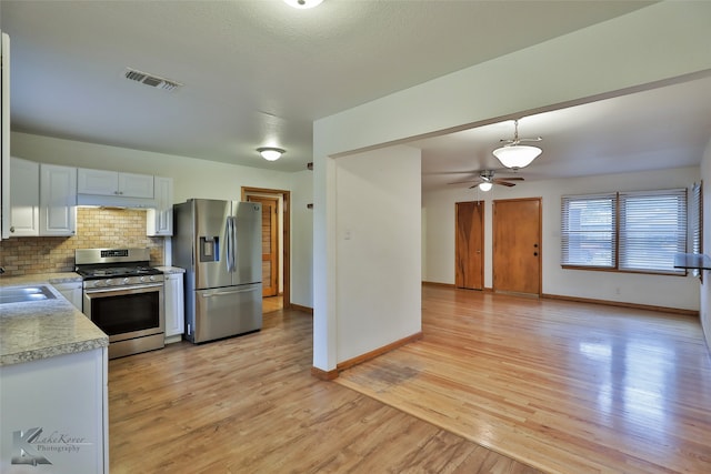 kitchen with white cabinets, hanging light fixtures, light hardwood / wood-style flooring, appliances with stainless steel finishes, and ceiling fan