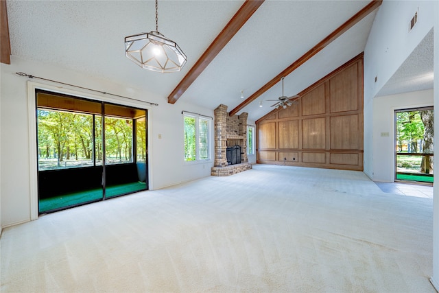 unfurnished living room with a fireplace, wooden walls, beamed ceiling, ceiling fan, and high vaulted ceiling