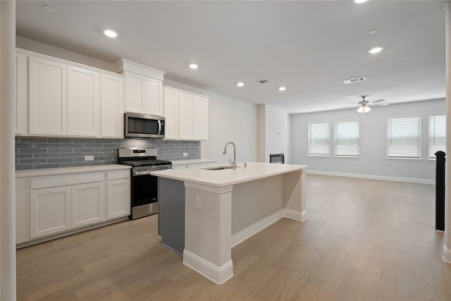 kitchen featuring white cabinets, sink, stainless steel appliances, and a center island with sink