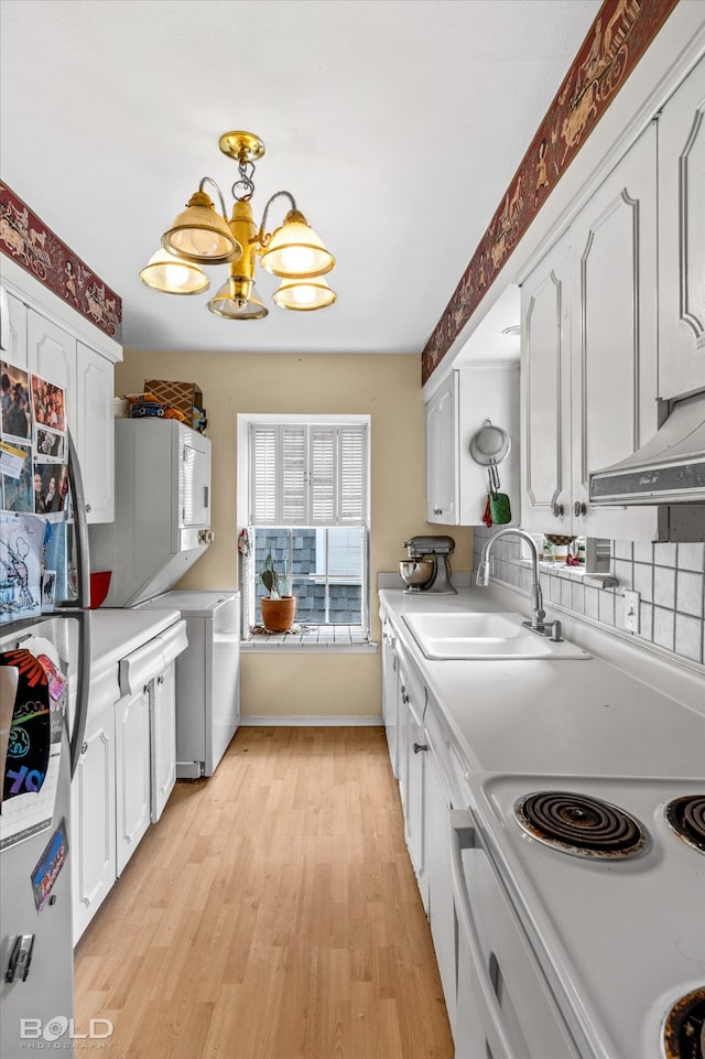 kitchen featuring light wood-type flooring, stainless steel fridge, white cabinetry, an inviting chandelier, and sink