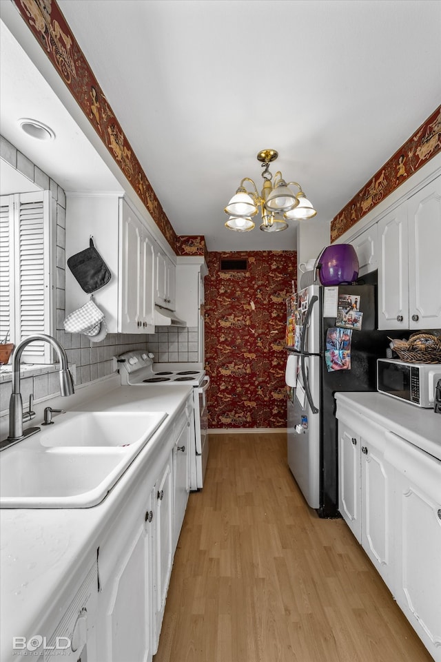 kitchen featuring range, a notable chandelier, sink, light wood-type flooring, and white cabinets