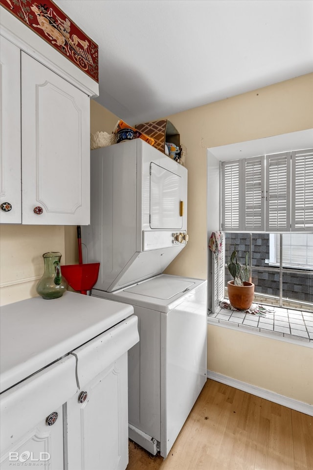 washroom with plenty of natural light, cabinets, stacked washer / dryer, and light wood-type flooring