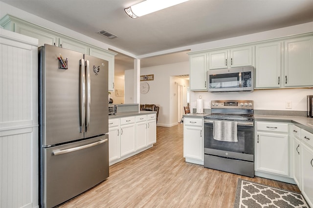 kitchen with appliances with stainless steel finishes, white cabinets, and light hardwood / wood-style floors