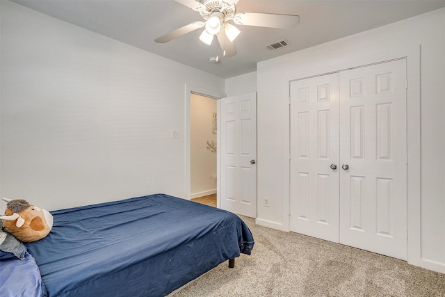 bedroom with a closet, ceiling fan, and light colored carpet