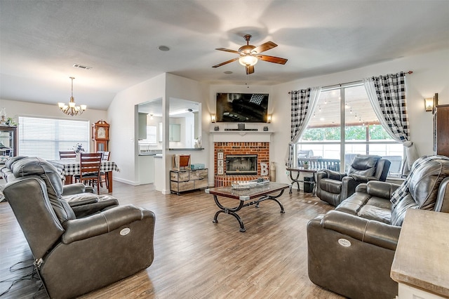 living room with a fireplace, ceiling fan with notable chandelier, a textured ceiling, lofted ceiling, and light hardwood / wood-style floors