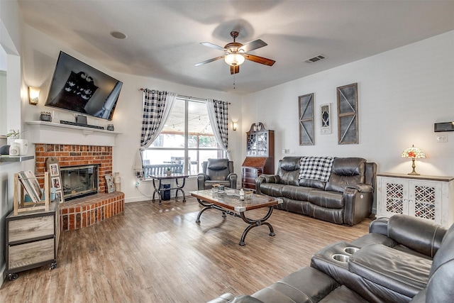 living room with ceiling fan, a fireplace, and light hardwood / wood-style flooring