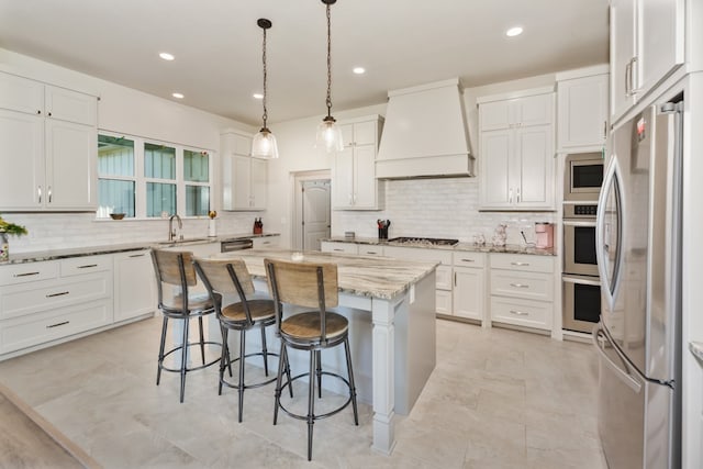 kitchen featuring white cabinets, appliances with stainless steel finishes, premium range hood, and a center island