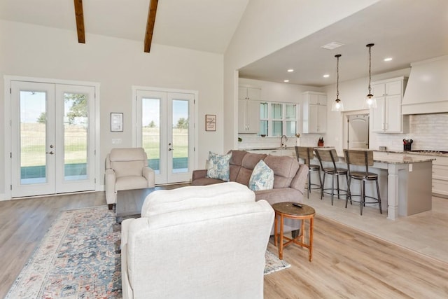 living room with light wood-type flooring, visible vents, recessed lighting, french doors, and vaulted ceiling with beams