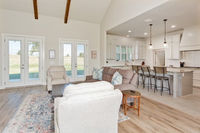 living room with light hardwood / wood-style floors, french doors, and a healthy amount of sunlight