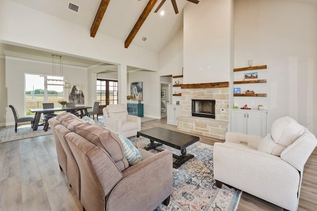 living room with visible vents, high vaulted ceiling, a fireplace, beamed ceiling, and light wood-type flooring