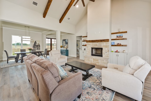 living room with a stone fireplace, beam ceiling, light hardwood / wood-style flooring, and high vaulted ceiling