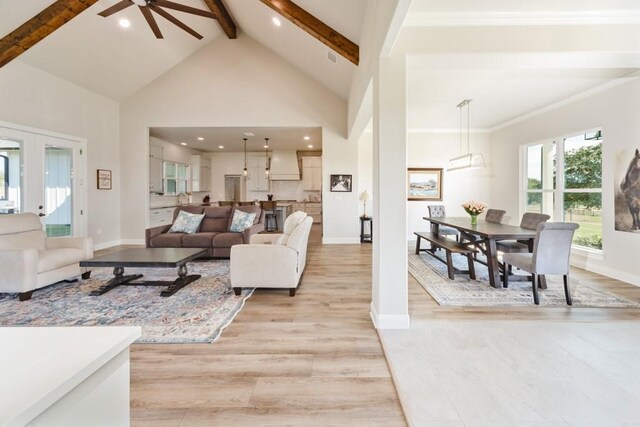 living room with baseboards, beamed ceiling, light wood-style flooring, french doors, and high vaulted ceiling