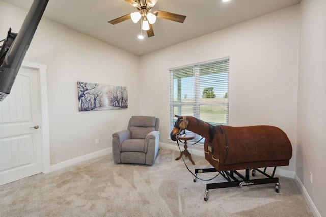 living area with baseboards, carpet, and a ceiling fan