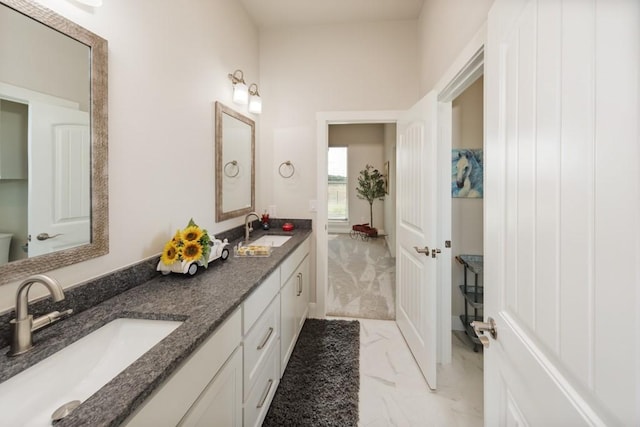 full bathroom featuring double vanity, marble finish floor, and a sink