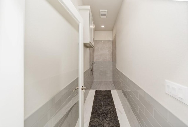 hallway with tile patterned floors, recessed lighting, and tile walls