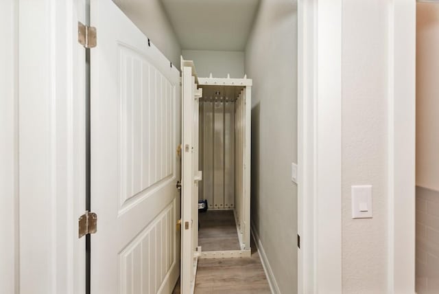 corridor with baseboards and light wood-style floors