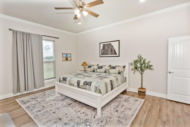 bedroom featuring ceiling fan, baseboards, light wood-style flooring, and crown molding