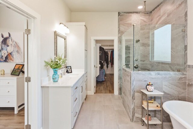 full bathroom with a walk in closet, tile walls, a freestanding bath, a stall shower, and vanity