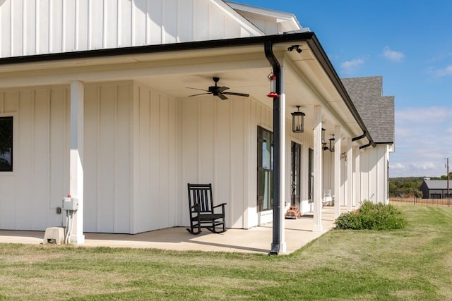 back of property featuring a lawn, board and batten siding, and ceiling fan