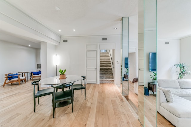 dining area with crown molding and light wood-type flooring