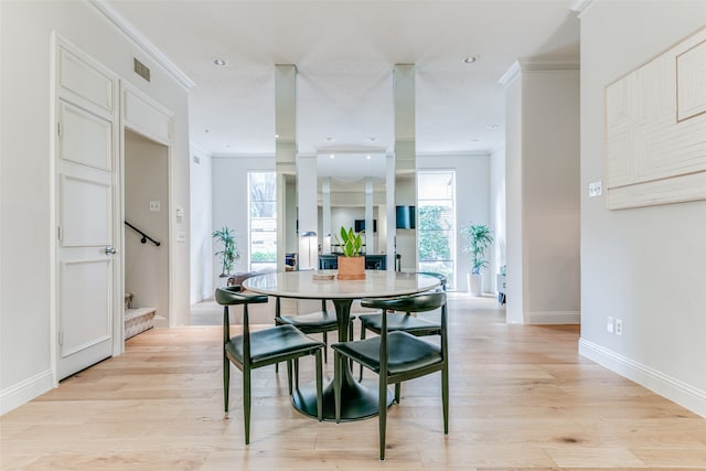 dining room with crown molding and light hardwood / wood-style flooring