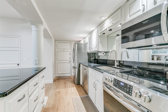 kitchen featuring white cabinets, light wood-type flooring, appliances with stainless steel finishes, ornate columns, and sink