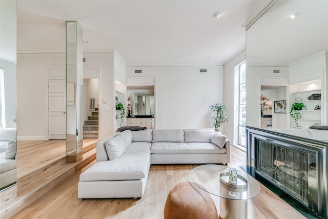 living room with light wood-type flooring and crown molding