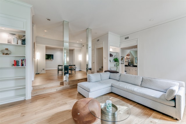 living room featuring ornamental molding, light hardwood / wood-style flooring, and built in shelves