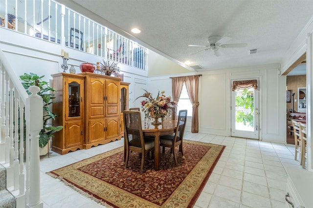 tiled dining room with ceiling fan and a textured ceiling