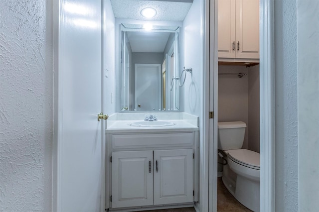 bathroom featuring vanity, toilet, and a textured ceiling