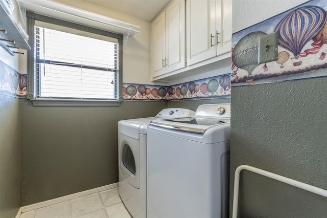 clothes washing area featuring cabinets, washer and clothes dryer, and light tile patterned floors