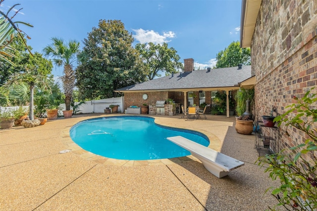 view of pool with a diving board and a patio area