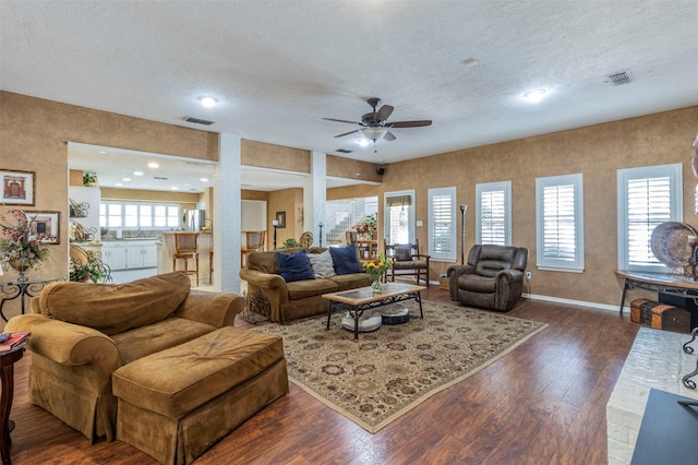 living room with ceiling fan, a textured ceiling, and dark hardwood / wood-style flooring