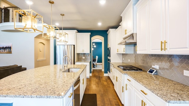 kitchen with stainless steel appliances, hanging light fixtures, and an island with sink