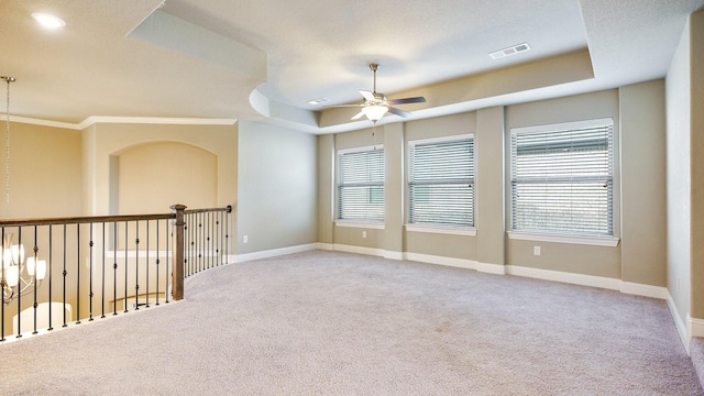 carpeted empty room with a raised ceiling and ceiling fan