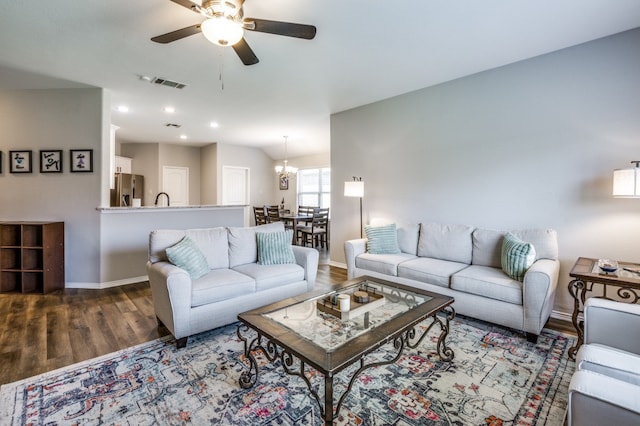 living room with ceiling fan with notable chandelier, wood-type flooring, and vaulted ceiling